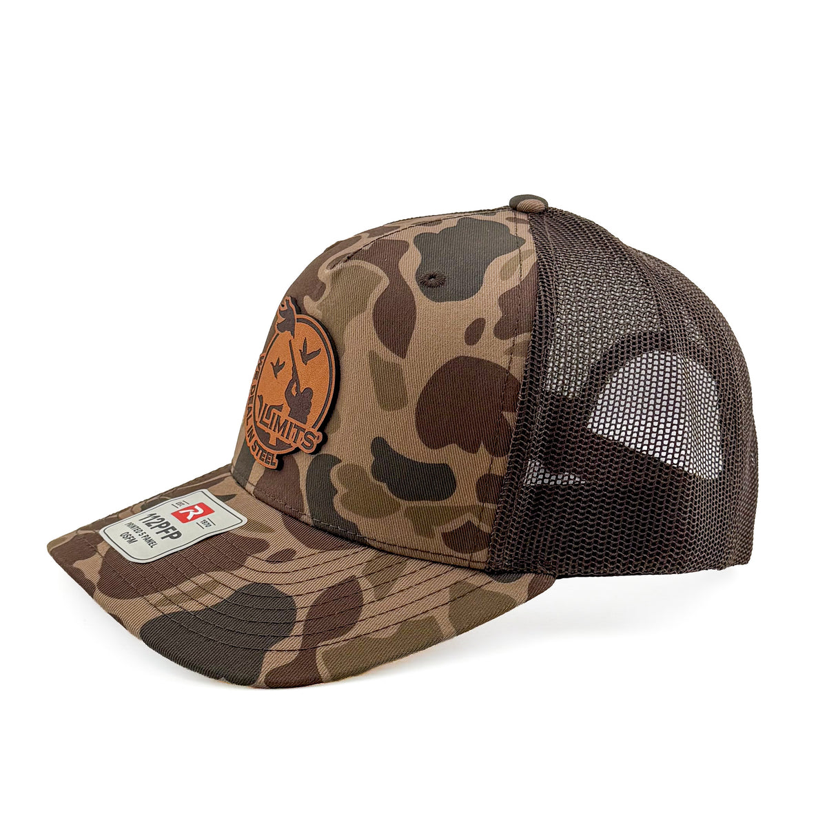 A camouflage trucker hat with brown mesh back panels and a circular brown leather patch on the front. The Limits patch features a duck silhouette and the text 'WE DEAL IN STEEL'.