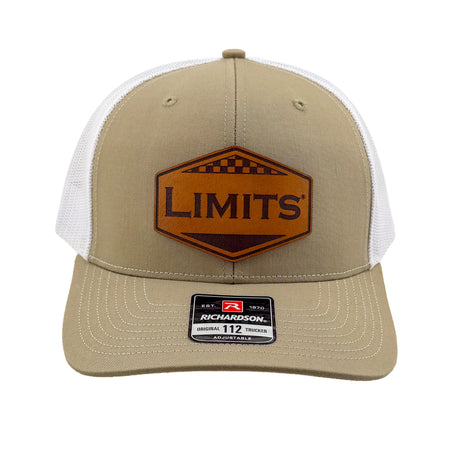 A trucker hat with a Khaki front panel and brim, white mesh back, and a brown leather patch on the front that reads 'LIMITS'. A size sticker for 'RICKMARDSON 112' is visible on the brim.