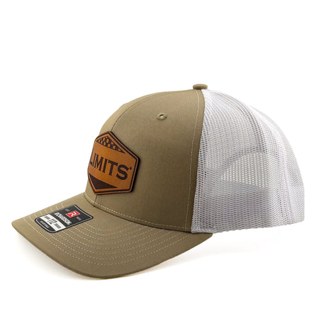 A trucker hat with a Khaki front panel and brim, white mesh back, and a brown leather patch on the front that reads 'LIMITS'. A size sticker for 'RICKMARDSON 112' is visible on the brim.