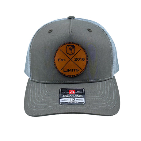 A Richardson 112fp trucker hat with a Beetle colored front and a Quarry colored mesh back, featuring a circular brown leather patch on the front with 'EST. 2016 LIMITS' logo.