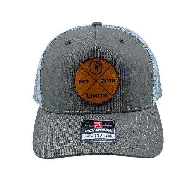 A Richardson 112fp trucker hat with a Beetle colored front and a Quarry colored mesh back, featuring a circular brown leather patch on the front with 'EST. 2016 LIMITS' logo.