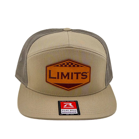 A beige and gray trucker hat with a brown leather patch on the front that reads 'LIMITS' and a 'Flat Bill Snapback' sticker on the brim, shown against a plain white background.